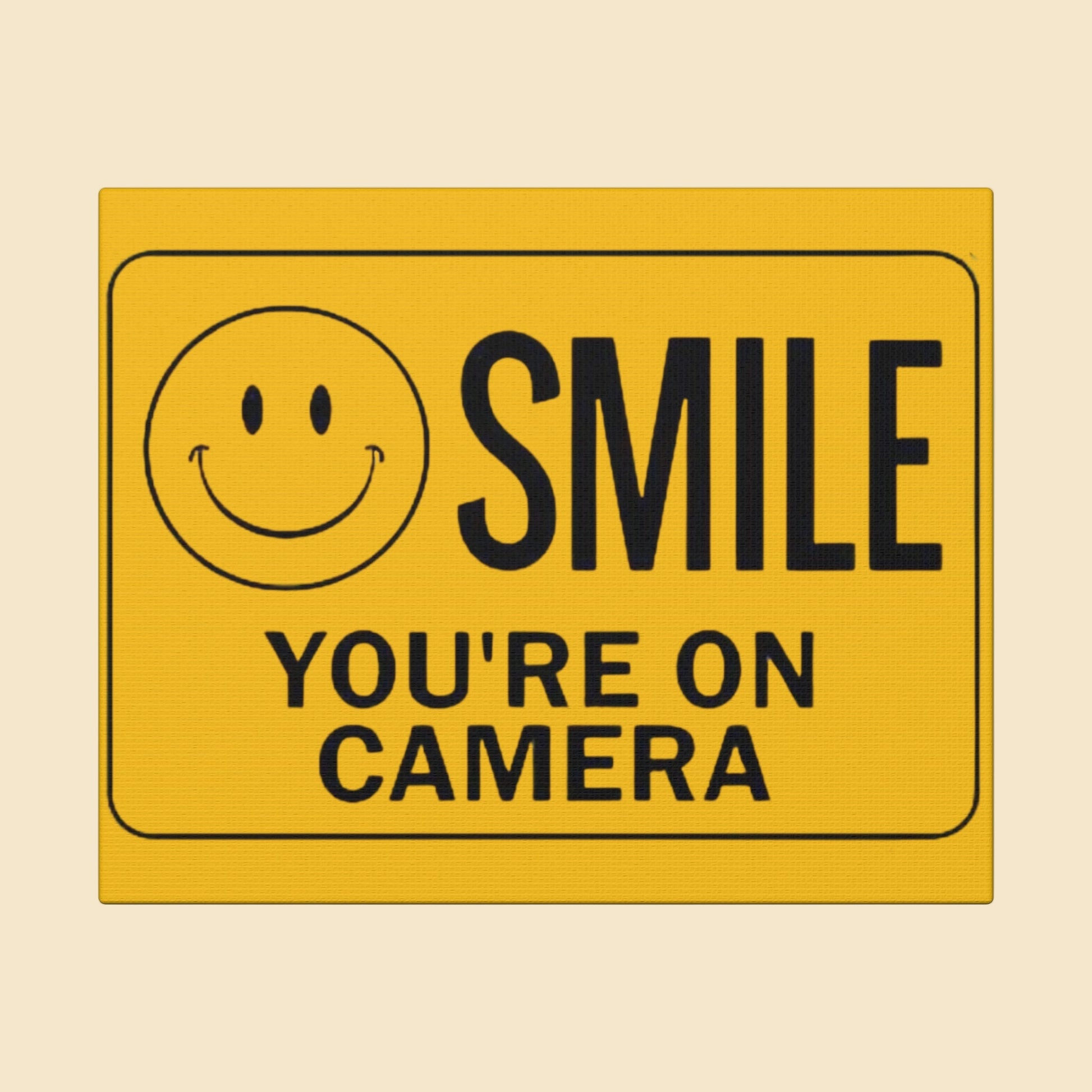 Yellow security camera sign with smiley face and text 'SMILE YOU'RE ON CAMERA' on a white background
