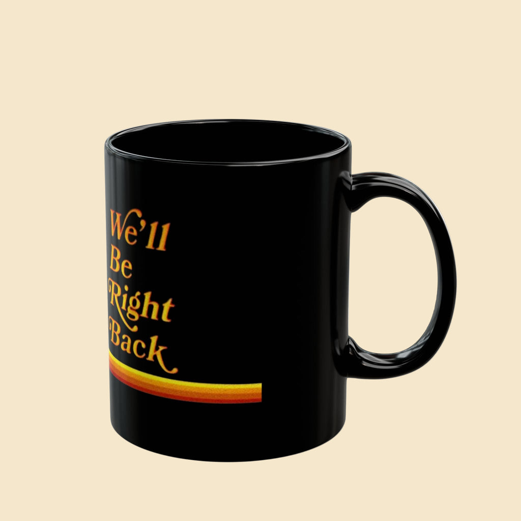 Black mug with yellow text 'We'll Be Right Back' on a white background