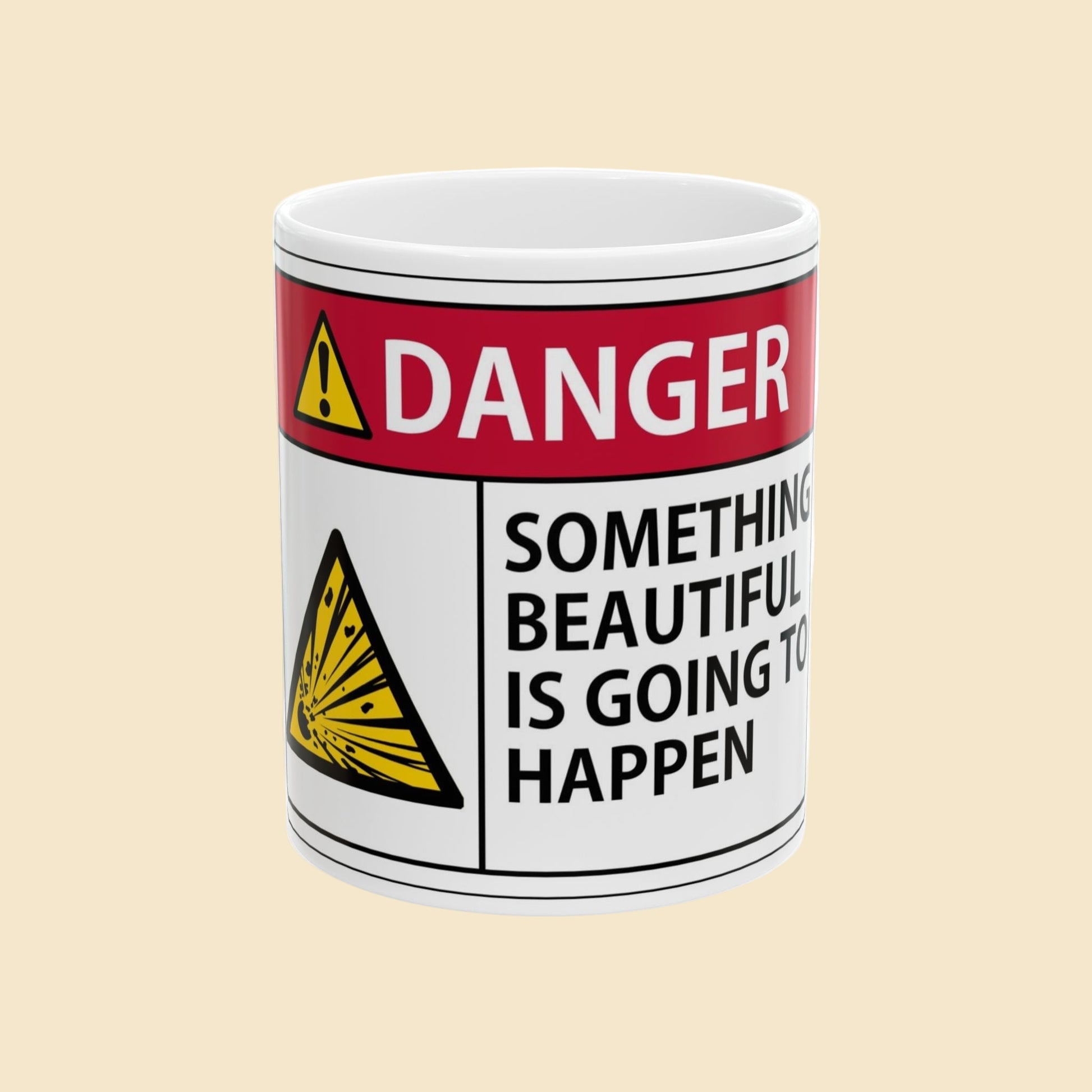 Mug with a warning label designating 'Danger: Something Beautiful is Going to Happen' on a beige background