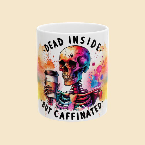 Mug with a colorful skeleton holding a coffee cup and text 'Dead Inside, But Caffinated' on a white background.