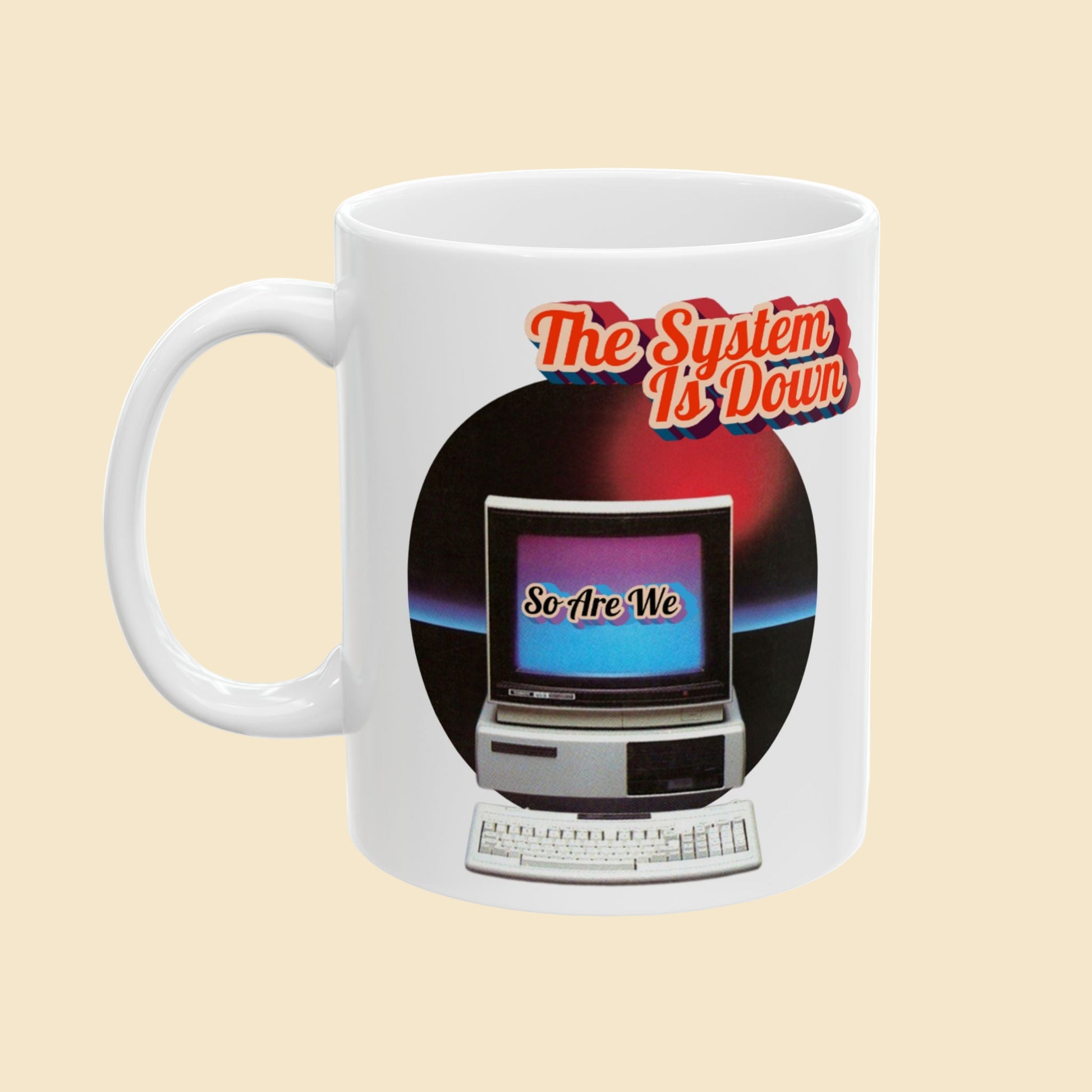 White mug with a retro computer graphic and text 'The System Is Down, So Are We' on a white background