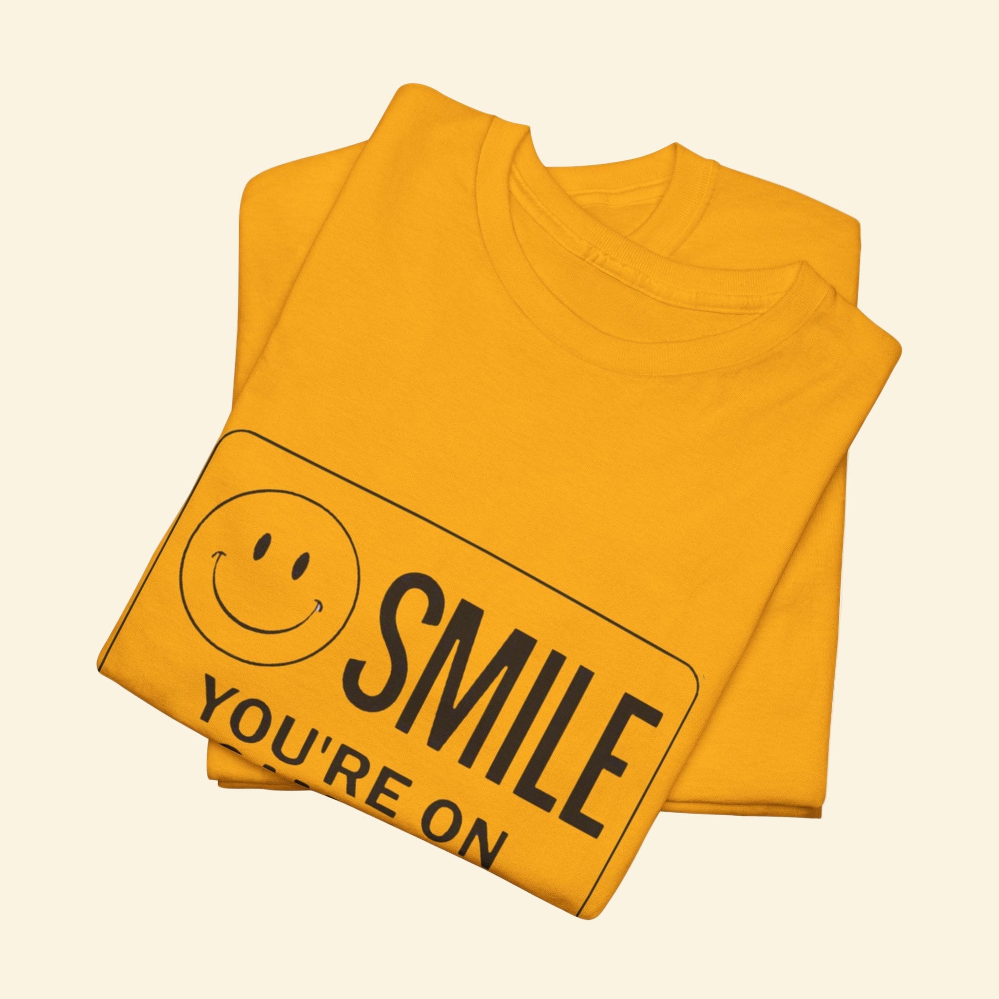 Yellow t-shirt with smiley face and text 'SMILE YOU'RE ON' on a beige background